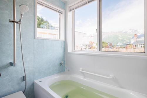 a bathroom with a bath tub and a window at Hakuba Highland Hotel in Hakuba