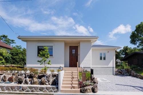 a small white house with a driveway at New Villa Natural J 伊豆高原 城ヶ崎海岸 in Ito
