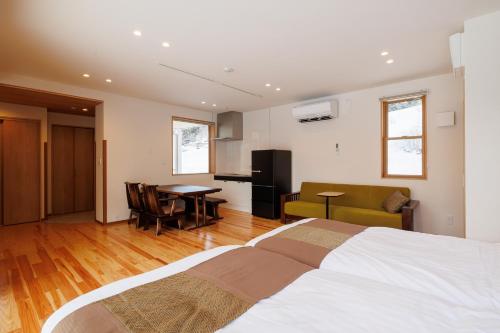 a bedroom with a large bed and a dining room at Hakuba Highland Hotel in Hakuba
