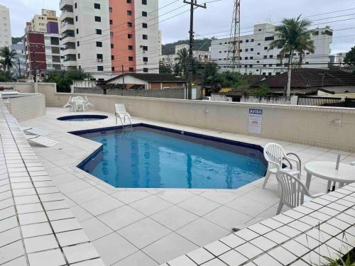 a swimming pool with two chairs and a table at Ap com varandas e ar condicionados nos quartos in Guarujá