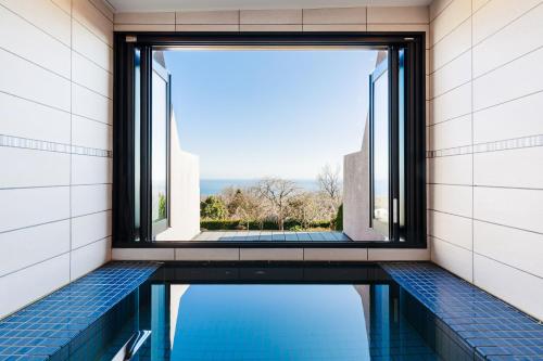 a swimming pool with a window in a building at the salon 伊豆高原 Hotels & Resort in Ito