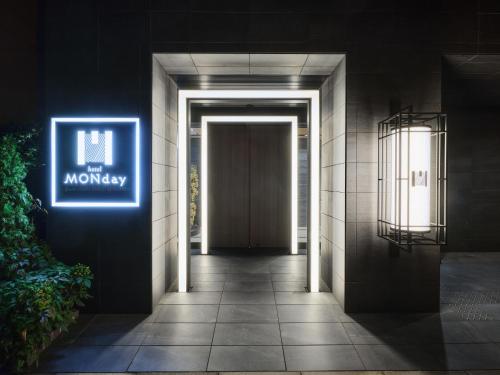 a hallway leading to a door with a monopoly sign at MONday Apart Asakusabashi Akihabara in Tokyo