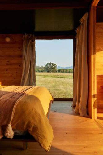 a bedroom with a bed and a large window at Dimensions X Farm-stay at Krinklewood Estate in Broke