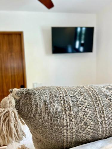 a pillow on a couch with a tv on the wall at Casita Palo Verde in San José del Cabo