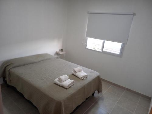 Un dormitorio con dos toallas en una cama con ventana. en Departamentos TUNQUELEN, en Río Colorado