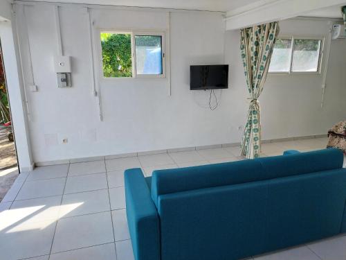 a living room with a blue couch and a tv at HELICONIA rostrata in Sainte-Rose