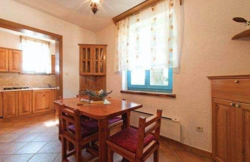 a kitchen with a wooden table and chairs in it at Ferienhaus In Radići Mit Privatem Pool in Jakići