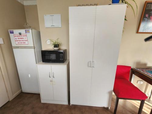 a kitchen with white cabinets and a microwave and a refrigerator at Guest Suite with private entry own kitchen and bathroom in Oamaru