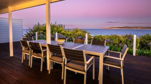 a dining table and chairs on a deck with a view of the ocean at Cactus- Spectacular Views On The Ocean Front Pet friendly in Emu Bay