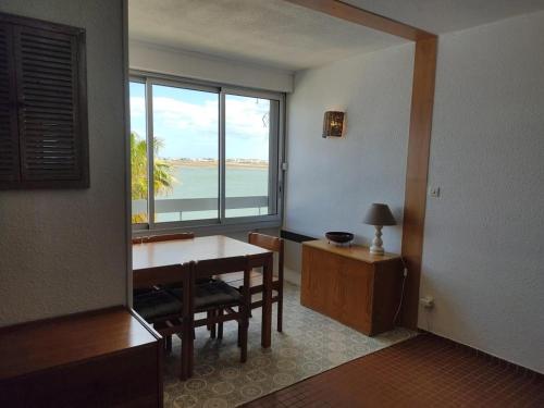 une salle à manger avec une table et une grande fenêtre dans l'établissement Gruissan Grazel - T2 Confortable 4/5 Pers, PKG sécurisé, Proche plage - FR-1-796-59, à Gruissan