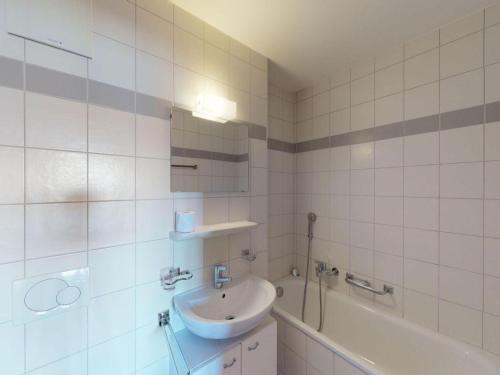 a white tiled bathroom with a sink and a tub at Spacious apartment in Nendaz in Nendaz