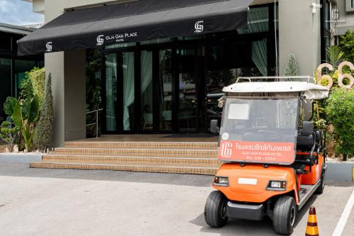 an orange golf cart parked in front of a building at Glai Gan Place Hotel in Sara Buri