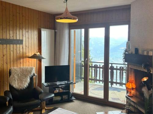 a living room with a television and a balcony at Sunny apartment with outdoor dinning in Veysonnaz