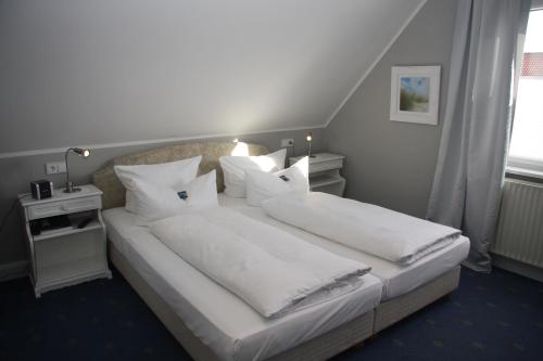 a bedroom with a large bed with white sheets and pillows at Hotel Christiansen in Tinnum