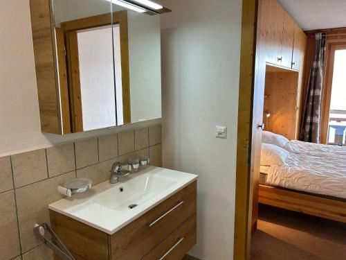 a bathroom with a sink and a mirror and a bed at Pleasant apartment with balcony in Veysonnaz