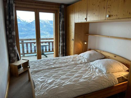 a bedroom with a bed with a view of a mountain at Pleasant apartment with balcony in Veysonnaz