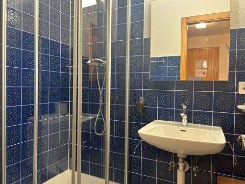 y baño de azulejos azules con lavabo y ducha. en Charming apartment in Vaysonnaz, en Veysonnaz