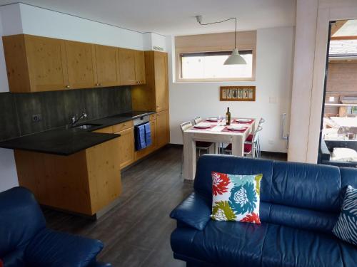a living room with a blue couch and a kitchen at Hotel Mont.Lac in Champex