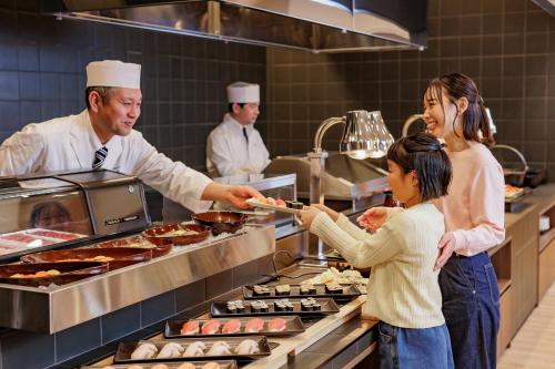 a group of people standing in a kitchen preparing food at KAMENOI HOTEL Tazawako in Senboku