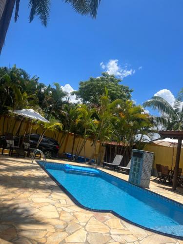 a swimming pool next to a resort with palm trees at Casa em Ilhabela - Próxima à Praia do Curral in Ilhabela