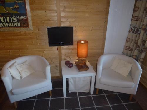 two chairs and a table with a tv in a room at Studio in Veysonnaz near Ski Lift in Veysonnaz