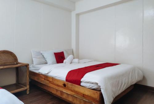 a bedroom with a bed with white and red sheets at RedDoorz @ Monterrazas Village Homestay Baguio in Baguio