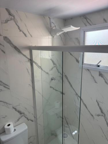 a bathroom with a glass shower and a toilet at Flats & Residence - Confort in Passo Fundo