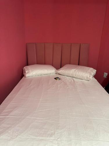 a bed with two pillows in a red room at Flats & Residence - Confort in Passo Fundo