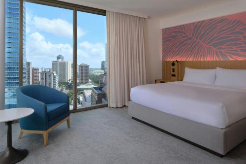a bedroom with a bed and a chair and a large window at Renaissance Honolulu Hotel & Spa in Honolulu