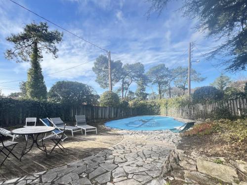 un patio avec une table et des chaises et une piscine dans l'établissement Maison rénovée avec piscine aux Abatilles, Arcachon - FR-1-474-274, à Arcachon