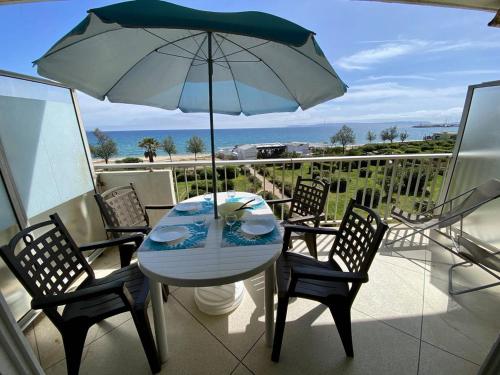 une table et des chaises avec un parasol sur un balcon dans l'établissement Appartement au Lavandou avec terrasse vue mer et parking - FR-1-816-17, au Lavandou