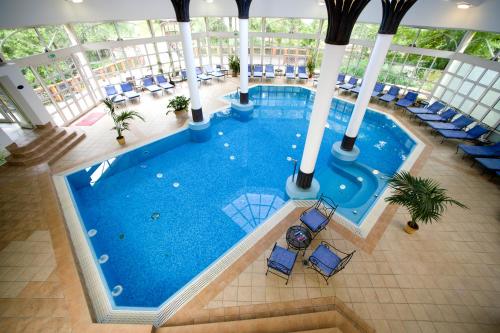 an overhead view of a large swimming pool with blue chairs at Szidónia Castle in Röjtökmuzsaj