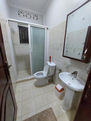 a bathroom with a toilet and a sink and a shower at Buwate Hill view Luxury Suites in Kampala