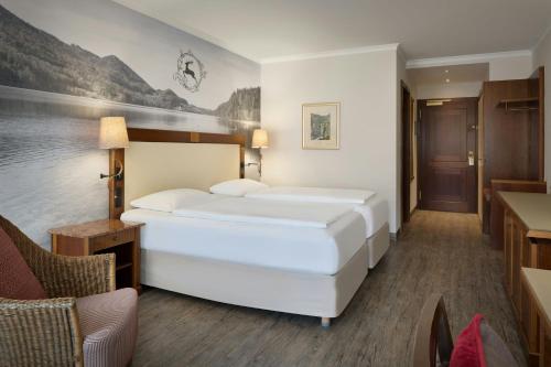 a bedroom with a large white bed in a room at Arabella Jagdhof Resort am Fuschlsee, a Tribute Portfolio Hotel in Hof bei Salzburg