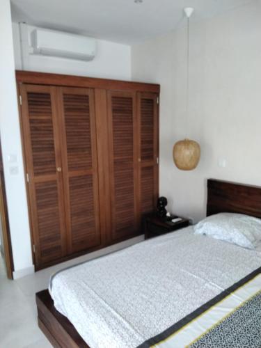a bedroom with a bed and a wooden closet at Villa la Canne Mapou No10 2chambres in Saint-Pierre