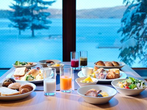 THE FOREST AKAN Tsuruga Resort في Akankohan: طاولة مع أطباق من الطعام وكؤوس من الحليب