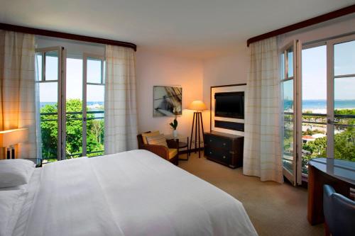 a bedroom with a white bed and large windows at Sheraton Sopot Hotel in Sopot