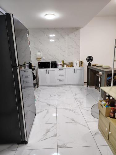 a kitchen with white marble floors and a black refrigerator at D Banyan Homestay, Bukit Banyan in Sungai Petani