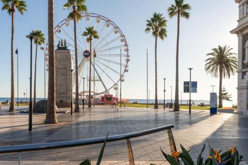 a ferris wheel in a park with palm trees at Belle Escapes - Ocean Views at the Bay in Glenelg