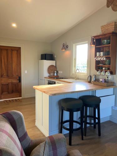a kitchen with a large island with two bar stools at Gate Keepers Cottage in Tasman
