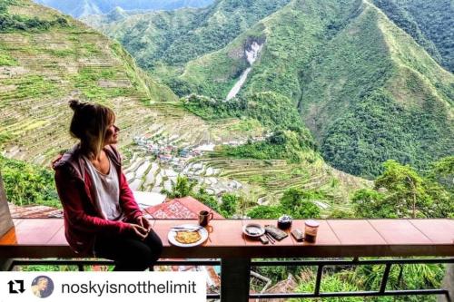 a woman sitting at a table with a view of a mountain at Batad Hillside Inn and Restaurant in Banaue