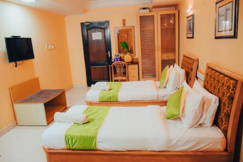 a hotel room with two beds and a television at Naksha Tree Hotels - Mogappair in Chennai