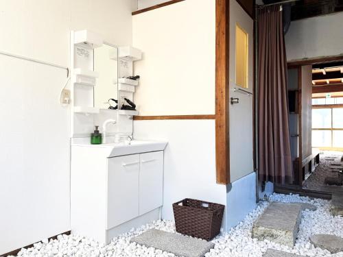 a kitchen with white walls and a counter top at 焼津 梔子 古民家の宿-カモメの鳴き声が聴こえる港町 in Yaizu