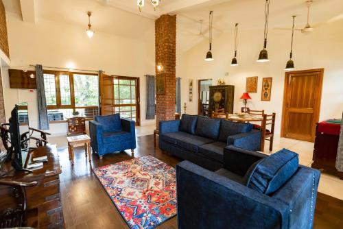 a living room with blue couches and a table at SaffronStays Doon Garden Villa - near Doon School and Mall Road in Dehradun