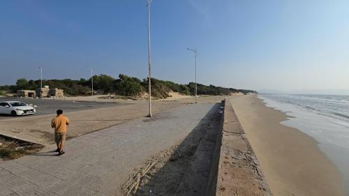 a man walking down a sidewalk next to the beach at ZoZo House - Homestay Bai Sau - bien Vung Tau in Vung Tau
