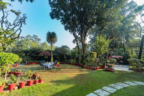 a garden with a table and chairs and flowers at SaffronStays Doon Garden Villa - near Doon School and Mall Road in Dehradun