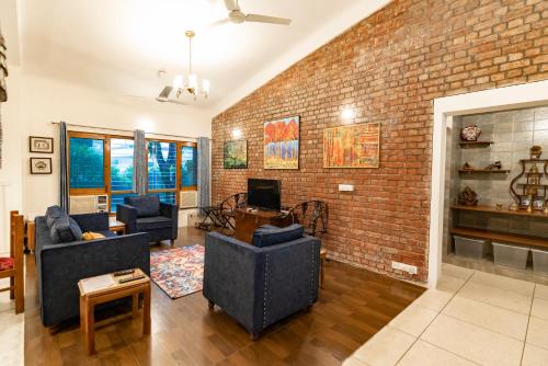 a living room with a brick wall at SaffronStays Doon Garden Villa - near Doon School and Mall Road in Dehradun