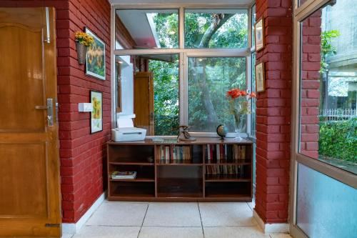 a room with a window and a book shelf with books at SaffronStays Doon Garden Villa - near Doon School and Mall Road in Dehradun