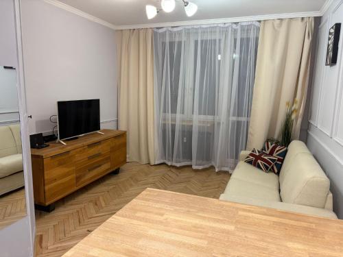 Apartament centrum في بياويستوك: غرفة معيشة مع أريكة وتلفزيون بشاشة مسطحة