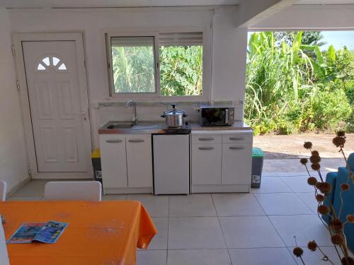 a kitchen with white cabinets and a sink and a table at HELICONIA rostrata in Sainte-Rose